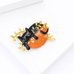 Detail of a lazy black enamel cat brooch with orange round base and golden branch detail