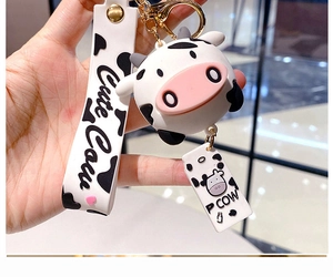 Detailed view of a cute silicone cow keychain with a branded wrist strap and gold hardware
