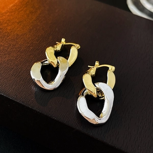 Detail shot of mixed gold and silver interlocking chain earrings on a dark wood background