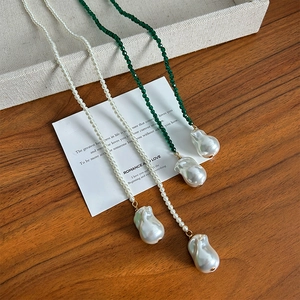 Baroque pearl necklace with green spinel beads on wood table, elegant French style jewelry