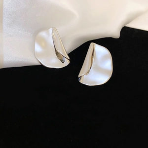 Macro shot of silver metal stud earrings featuring a modern irregular fold design