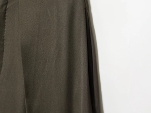 Makroaufnahme der dunkeloliven Twill-Stoffstruktur und detaillierte Faltennaht an der Hose