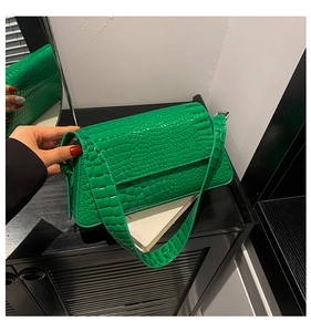 Close-up of green crocodile-textured leather handbag with classic flap and sturdy strap