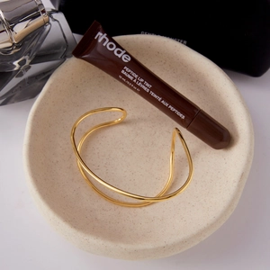 Detail shot of golden double-line open cuff bracelet styled with elegant lifestyle props