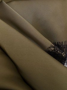 Macro d'un tissu satiné vert olive avec une bordure en dentelle de cils noirs fins