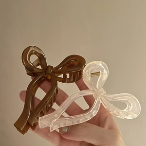 Pair of elegant ribbon-style bow hair claws in amber and translucent white colors