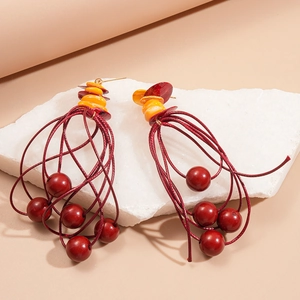 Close-up of bohemian acrylic bead tassel earrings with shell discs on white stone