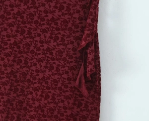 Detailed macro shot of wine red burnout velvet fabric with intricate floral patterns