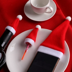 Mini red velvet Christmas hats for wine bottles and lollipops in a festive table setting