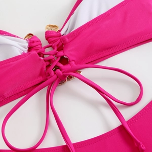 Détail du bikini rose vif avec lanières à lacets et ornements en métal doré élégants