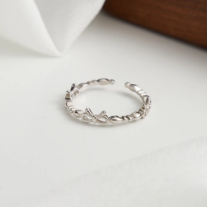 Macro shot of bow knot silver ring on wood stand with detailed bead texture band