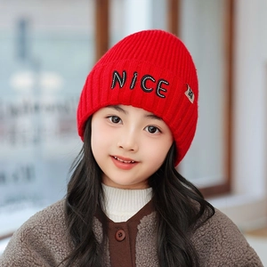 Close-up of red chunky knit beanie with white NICE embroidery and cozy ribbed texture