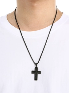 Détail d'un pendentif croix noir à texture carbone sur un mannequin en t-shirt blanc