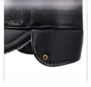 Detail of warm winter flat cap showing black leather texture and ear flap lining