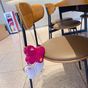 Detail of rose red and white butterfly-shaped chain bags with rainbow and floral motifs