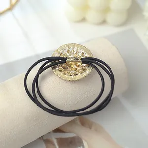 Gros plan du chouchou avec pendentif en métal doré creux et ciselure baroque florale