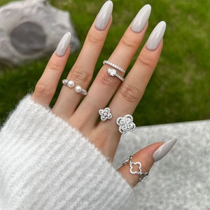 Detail view of silver rings with pearls and sparkling clover zircon on a natural stone base
