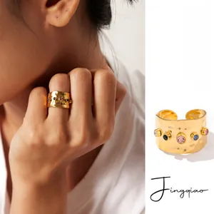 Makroaufnahme von 18K vergoldetem Ring mit Hammerschlag-Textur und bunten Edelsteinen
