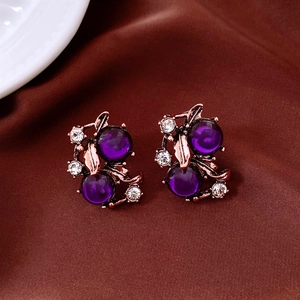 Detailansicht von Vintage-Blumenohrringen mit lila Perlen und Kristallen auf braunem Stoff