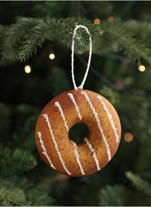 Close-up of a realistic doughnut Christmas ornament hanging on a pine tree with bokeh lights