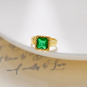 Macro shot of gold-plated ring with emerald green square stone and twisted border