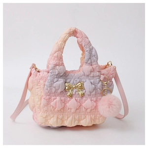 Detail of pink gradient pleated bag with golden bow hardware and plush ball charm