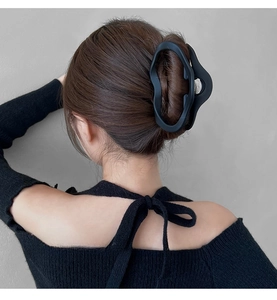 Close-up of large matte black irregular hair claw clip holding thick hair in a bun