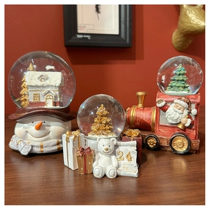 Close-up of Santa Claus and snowman Christmas crystal snow globes on a wooden table