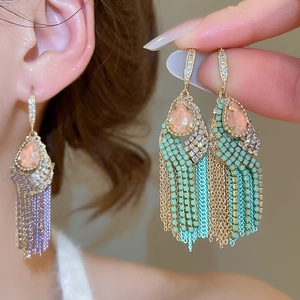 Detail showing gold tassel earrings with pink teardrop stones and colorful bead fringe