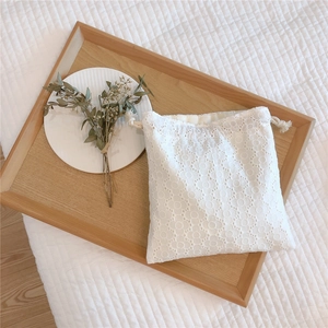 Detail of delicate white floral lace storage bag with woven cotton drawstring closure