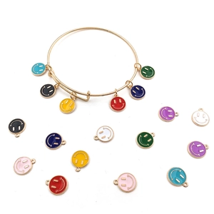 Close-up of colorful enamel smiley face charms on a gold bracelet over white background