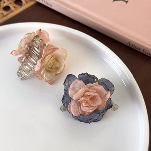 Detailed view of floral hair clips with fabric camellia petals on a white ceramic plate