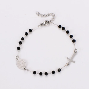 Detail of religious bracelet with black faceted beads, cross charm and medal