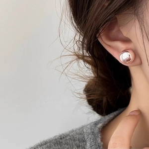 Close-up of elegant rose gold round stud earring worn by a model in soft lighting
