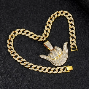 Macro shot of gold cuban chain and iced out 666 gesture pendant on black leather background