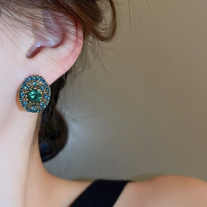 Close-up of vintage oval earrings featuring green crystal center and blue rhinestones