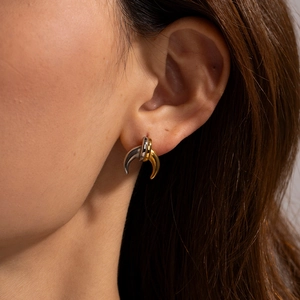 Close-up of a model wearing two-tone C-shaped hoop earrings in gold and silver finish