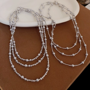 Détail d'un collier triple rang en perles argentées avec pendentif croissant de lune