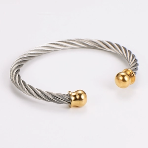 Close-up of dual-tone steel cable bangle featuring gold round beads and silver spiral wire