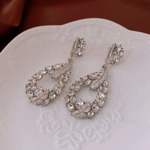 Detail of silver drop earrings with pavé crystals on a vintage ceramic display