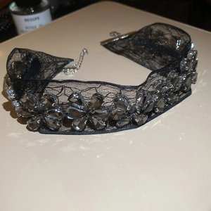 Détail d'un ras de cou en dentelle noire orné de cristaux gris en forme de fleur
