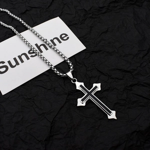 Detailed shot of a silver gothic cross pendant on a black box chain over dark background