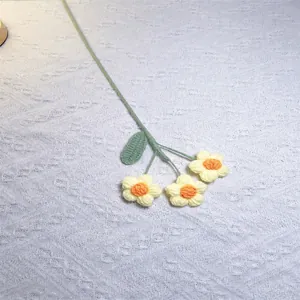 Detail of handmade crochet puff flowers with yellow petals on white textured fabric