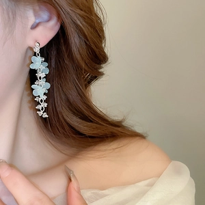 Detailed view of light blue flower tassel earrings with crystals on female model
