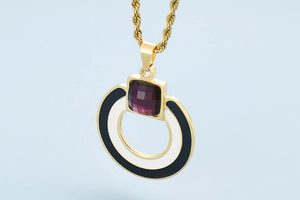 Macro view of gold twist chain necklace with black and white ring and purple gemstone