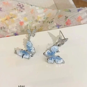 Detailansicht der Ohrringe mit blauem Kristallschmetterling auf einer weißen Geschenkkarte