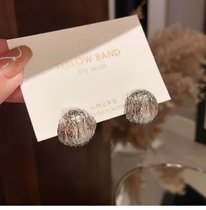 Detailed view of silver hemispherical stud earrings with textured matte brushed finish