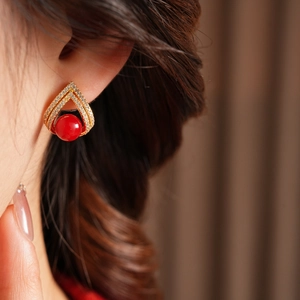 Vue macro latérale d'un mannequin portant des boucles d'oreilles dorées, perle rouge et zircons