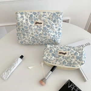 Close-up of two blue floral quilted makeup bags in different sizes with zipper closure