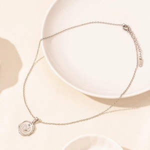 Detail of silver stainless steel necklace with blue rhinestone and baby footprint pendant